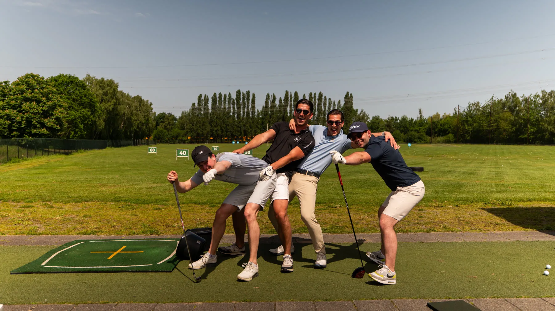 Vier deelnemers in een gelijke, licht belachelijke pose op de driving range